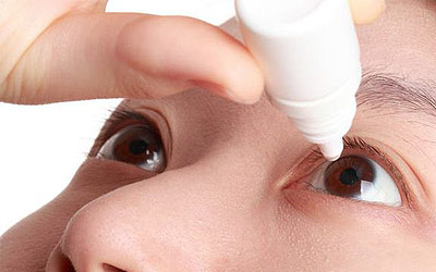 Man putting eyedrops into his eye